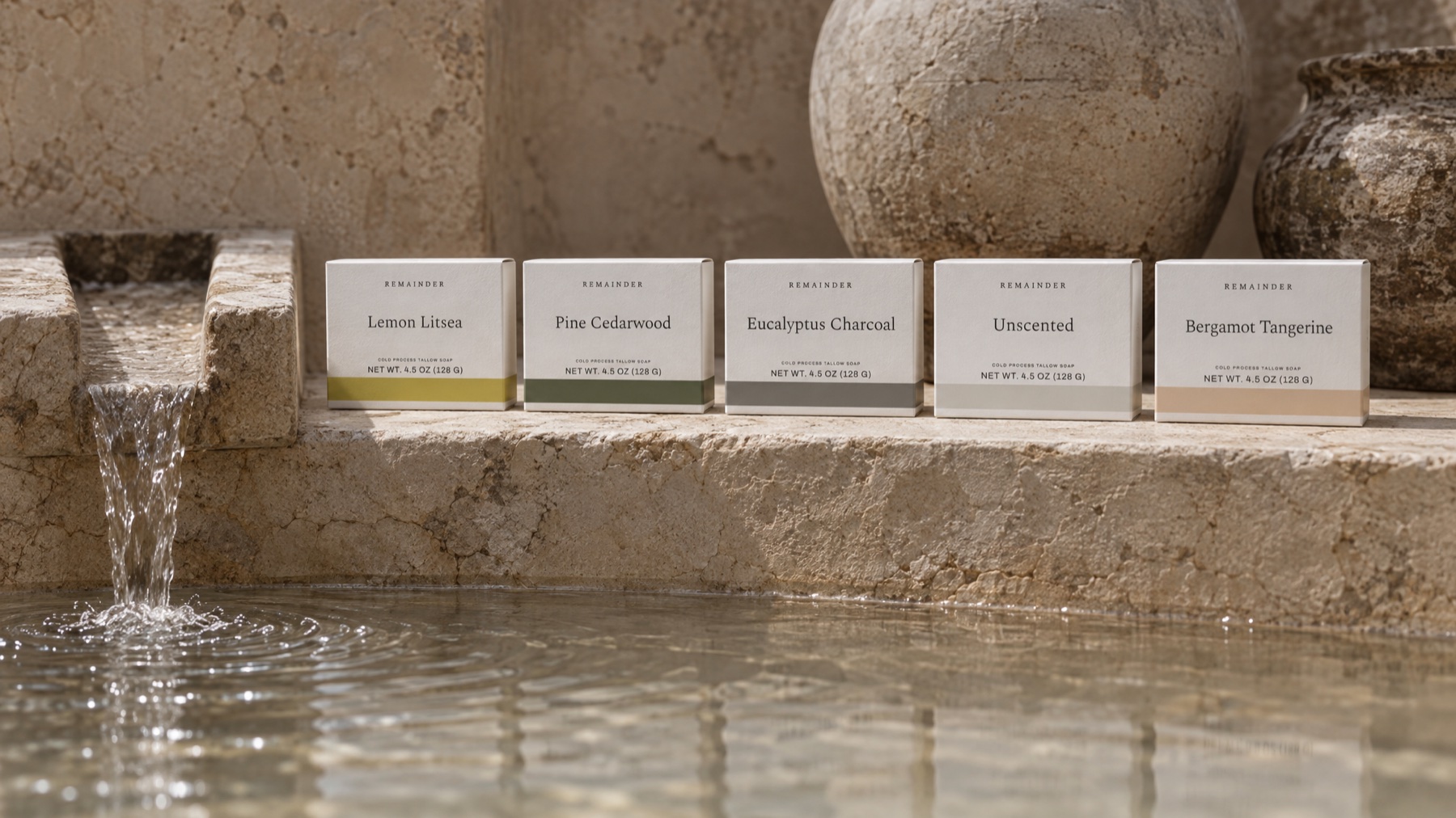 Five soap boxes on a limestone ledge above a stone pool with a spout